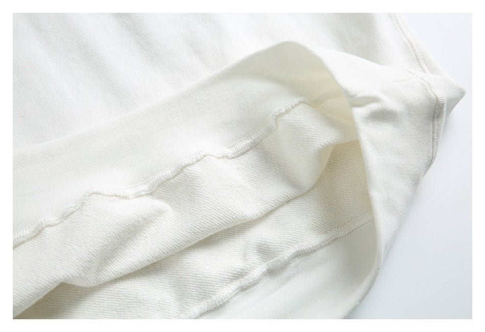 Close-up of white garment fabric showing a folded hem and visible stitching.