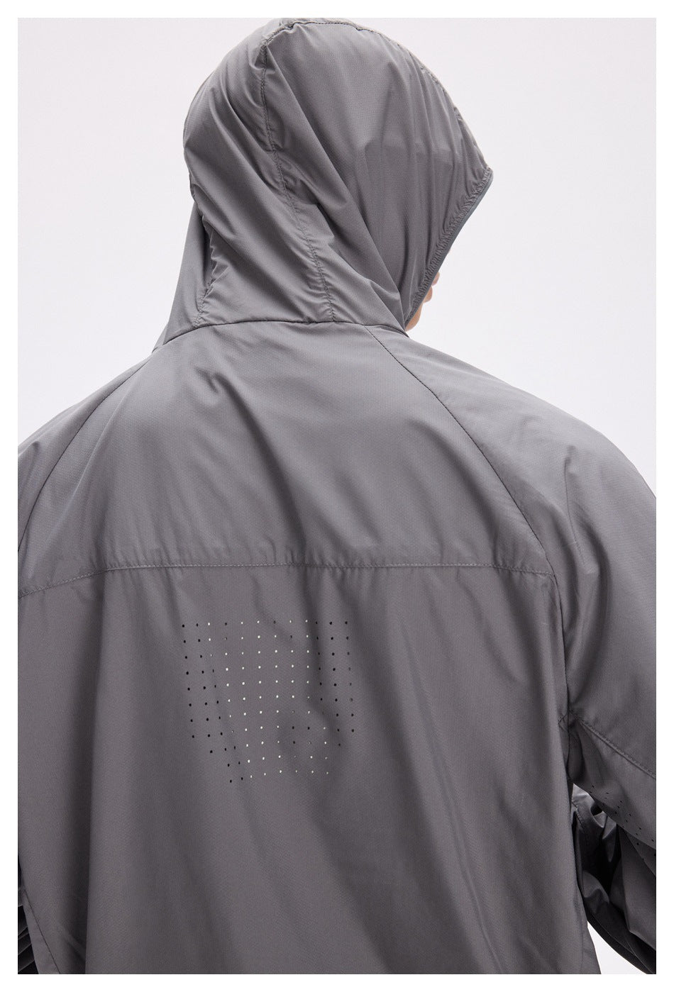 Close rear view of a model wearing a gray hooded jacket with a dotted pattern across the back.