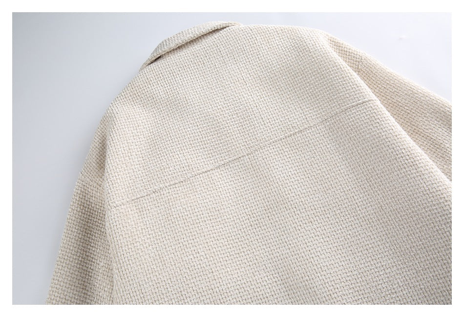 Close-up of a cream woven garment showing a curved seam and textured surface.