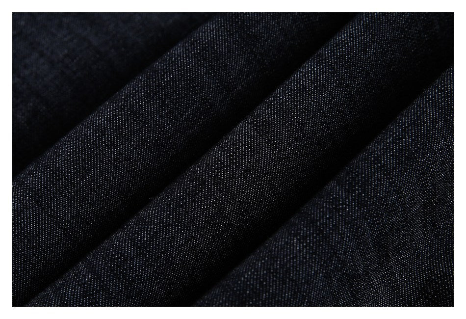 Macro view of dark indigo denim fabric in soft folds, showing its fine woven texture.