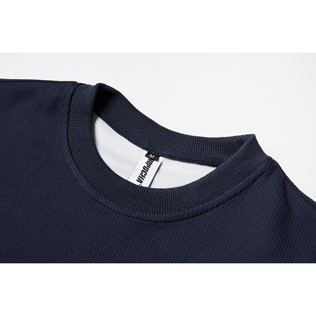 Close-up of a navy sweatshirt's ribbed crew neckline and inner neck label.