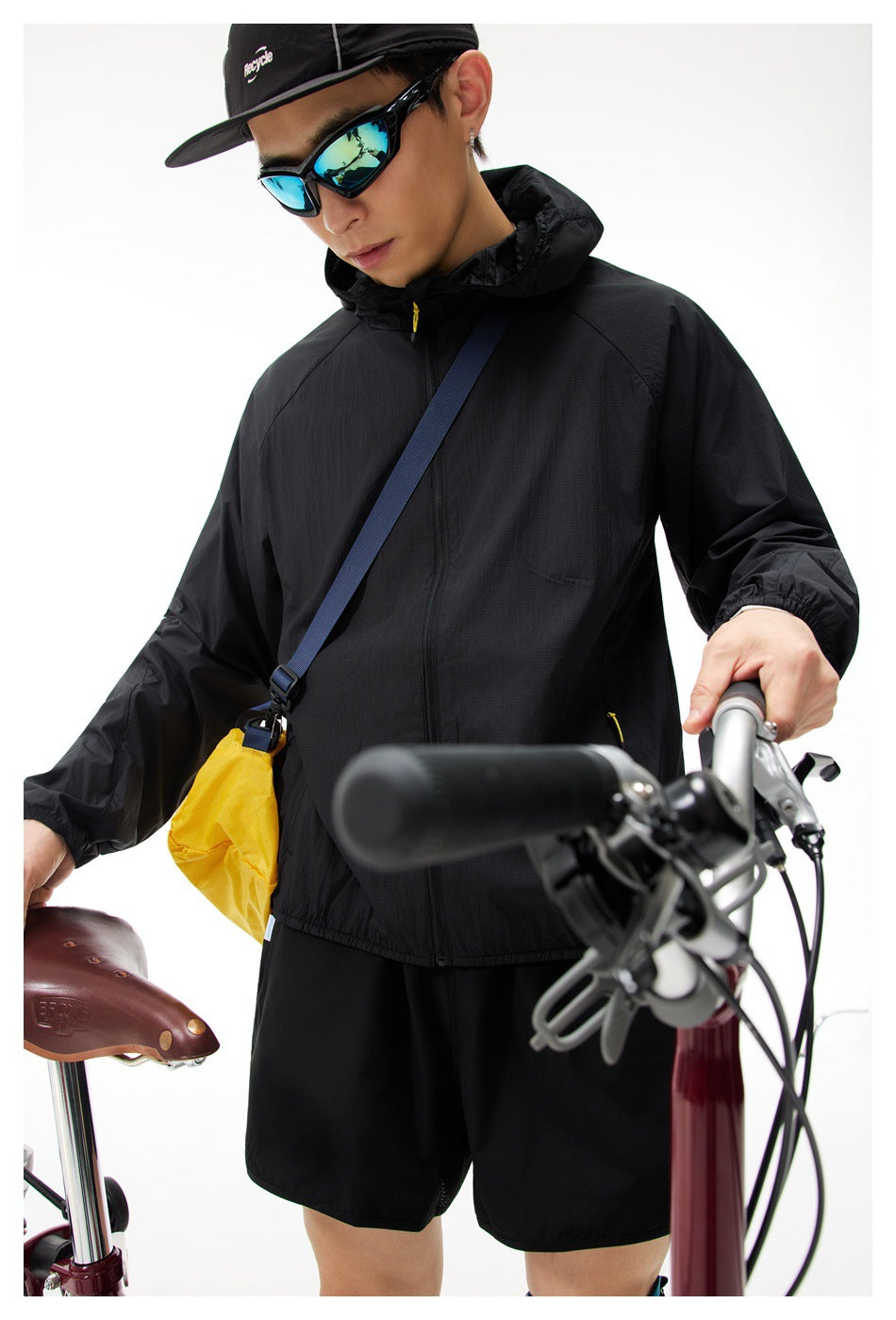 Close view of a person wearing a black hooded zip jacket with a crossbody bag, showing the textured fabric