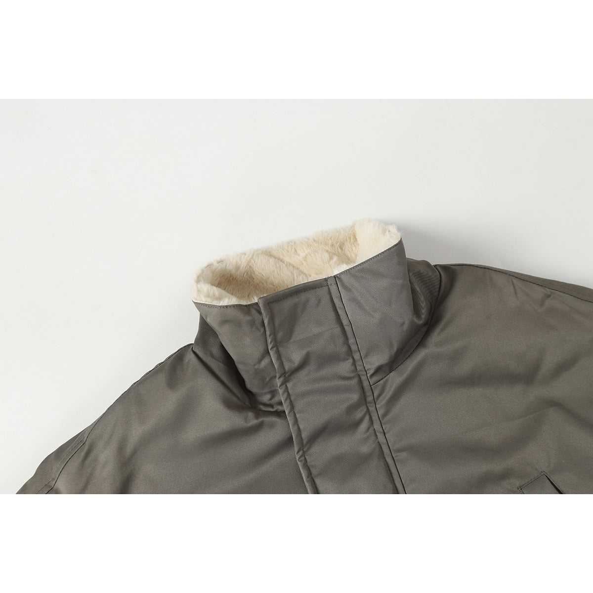 Close-up of a gray jacket’s high collar, showing its cream-colored plush lining and front storm flap.