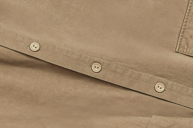 Close-up of tan garment fabric with a stitched button placket and three light-colored buttons.