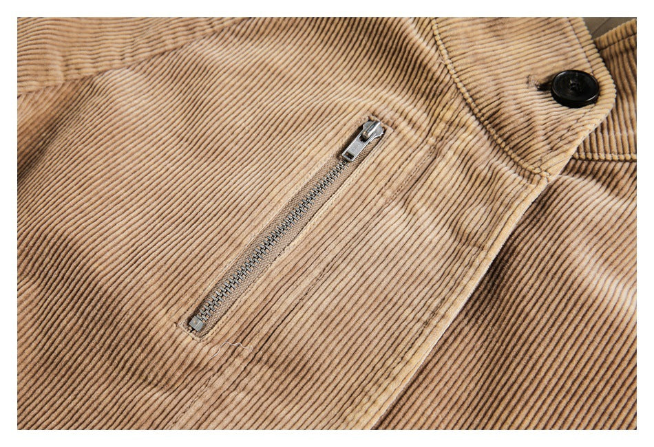 Close-up of a tan corduroy jacket's metal zip pocket and black collar button.