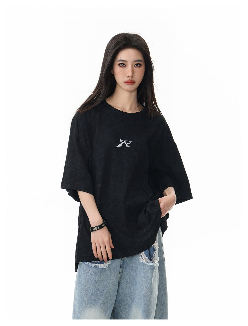 Closer front view of a model wearing an oversized black T-shirt with a small white chest emblem.
