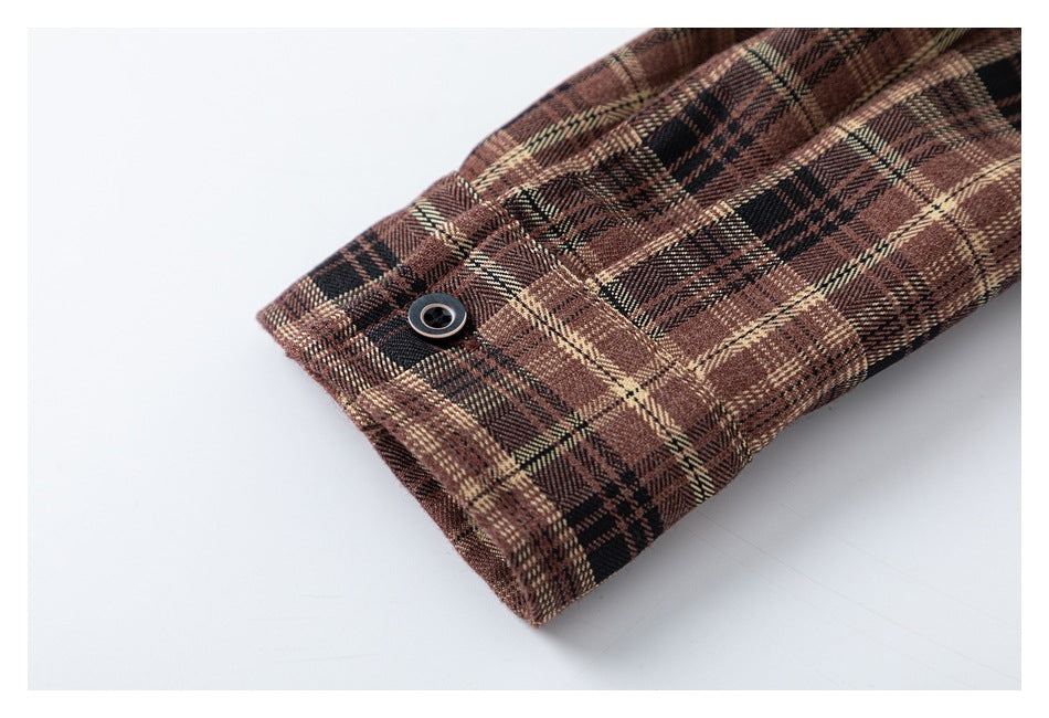 Close-up of the brown plaid shirt cuff and its dark button.