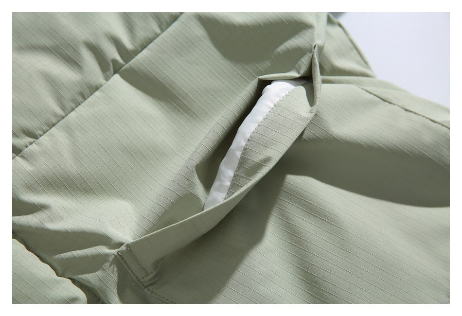 Close-up of a pale sage jacket pocket opening with white lining visible inside.