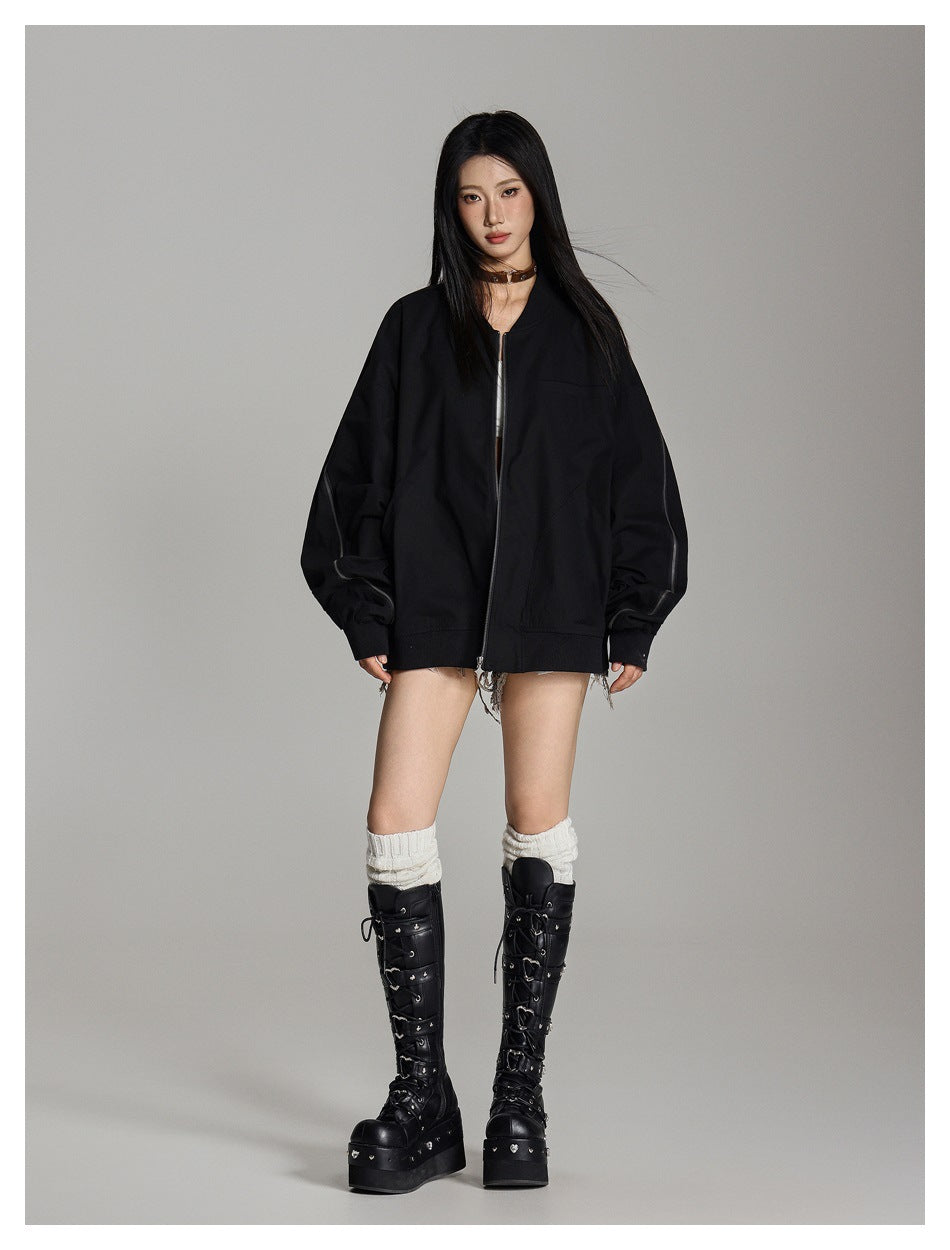Model wearing an oversized black zip bomber jacket with sleeve zippers, platform knee-high boots and white slouch socks