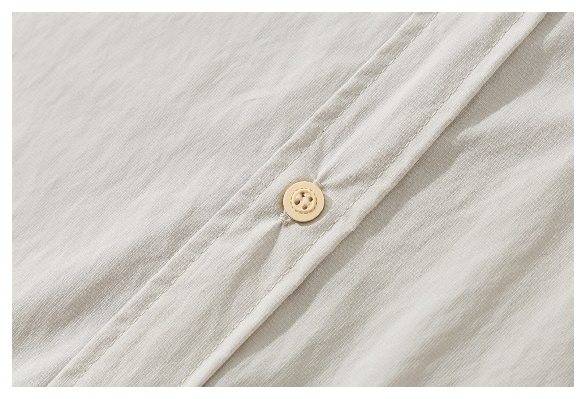 Close-up of the off-white shirt's front placket, stitching, and a beige button.