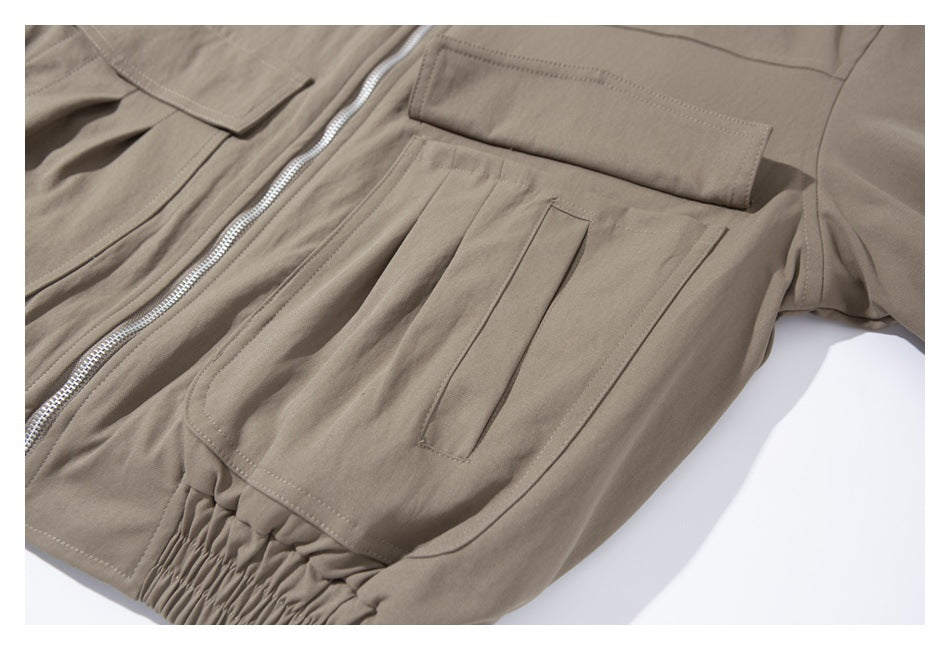Close-up of the taupe jacket's front pockets, silver zipper, and gathered elastic waist.