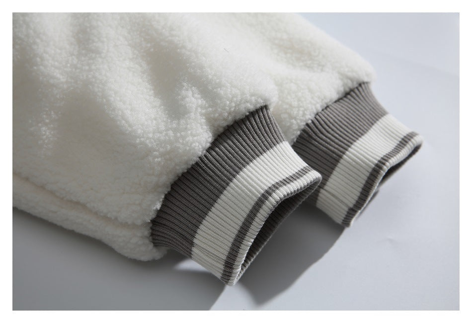 Close-up of a cream fuzzy jacket with gray-and-white striped ribbed cuffs.