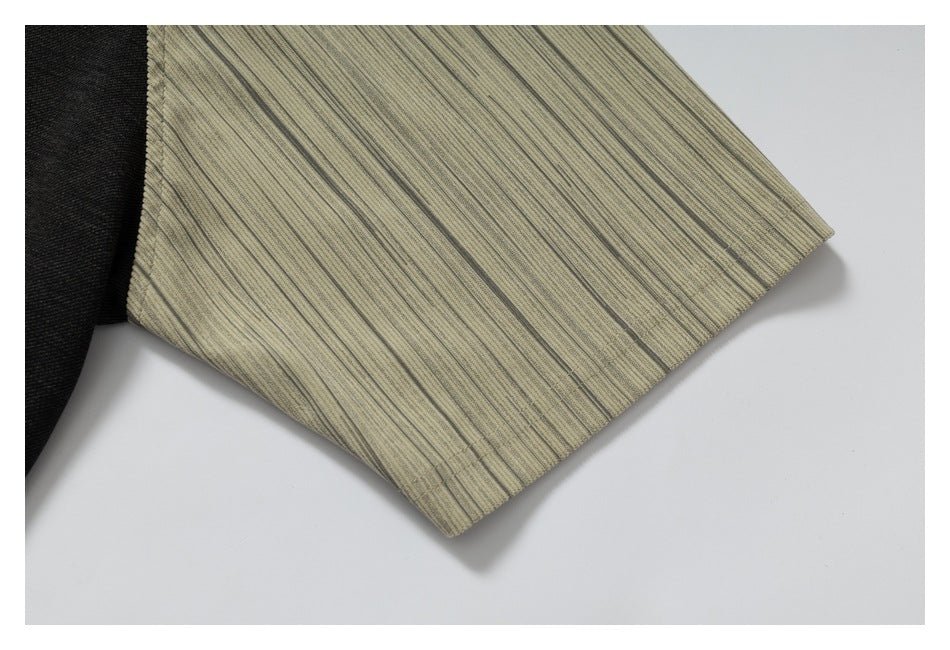Close-up of a beige sleeve with fine dark stripes and a stitched hem on the black raglan T-shirt.