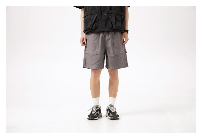 Front view of a model wearing gray cargo shorts with large patch pockets, shown from the waist down.