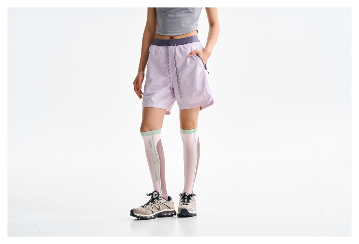 Cropped front view of a model in lilac drawstring shorts with zip pockets and pink knee-high socks.