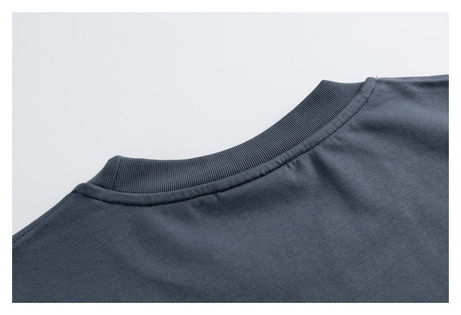 Close-up of the ribbed crew neckline and shoulder seam on a dark slate-gray shirt.