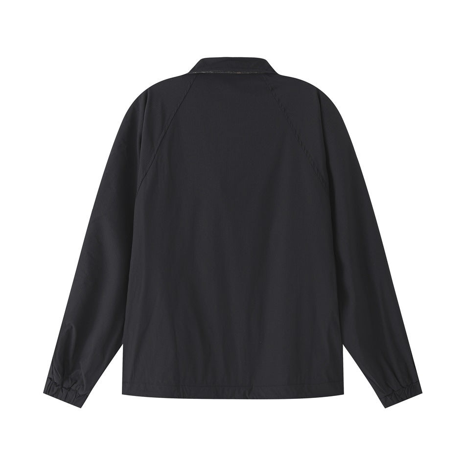 Back view of a black jacket with a pointed collar, raglan sleeves and gathered cuffs.