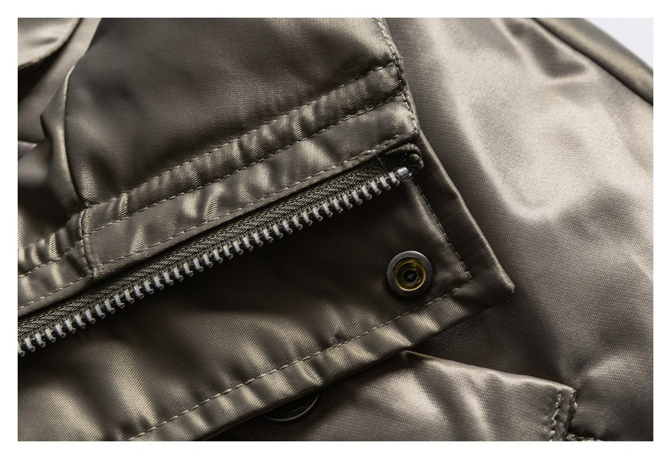 Close-up of a charcoal-olive garment zipper beneath a stitched flap with a snap fastener.