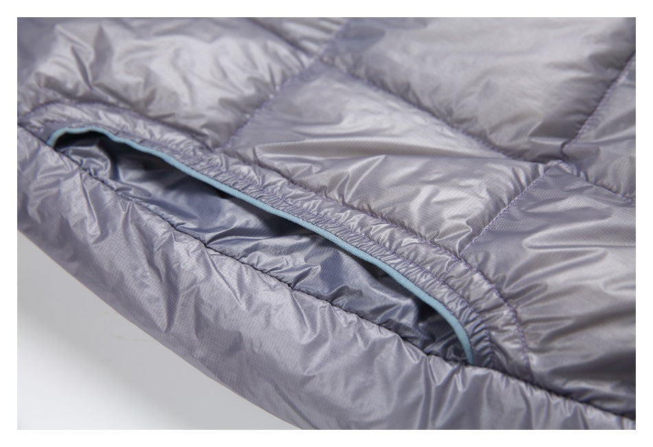 Close-up of a jacket pocket opening edged with pale blue trim against gray quilted fabric.