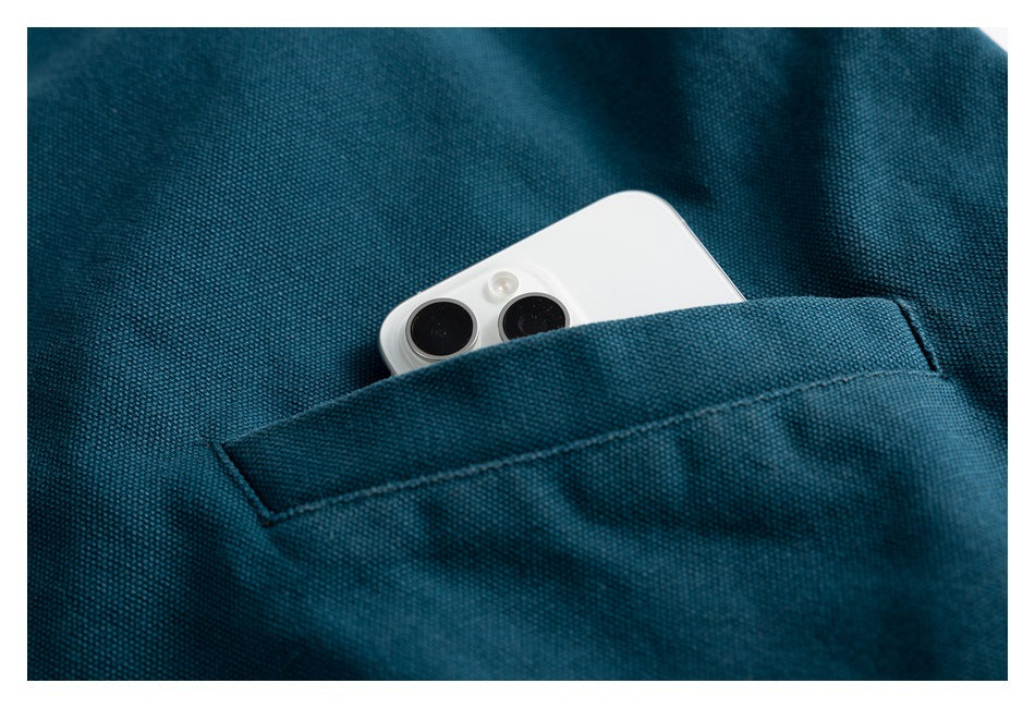 A white phone tucked into a pocket on teal textured fabric.