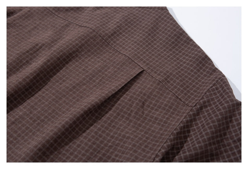 Close-up of a brown small-check shirt panel and stitched seam.