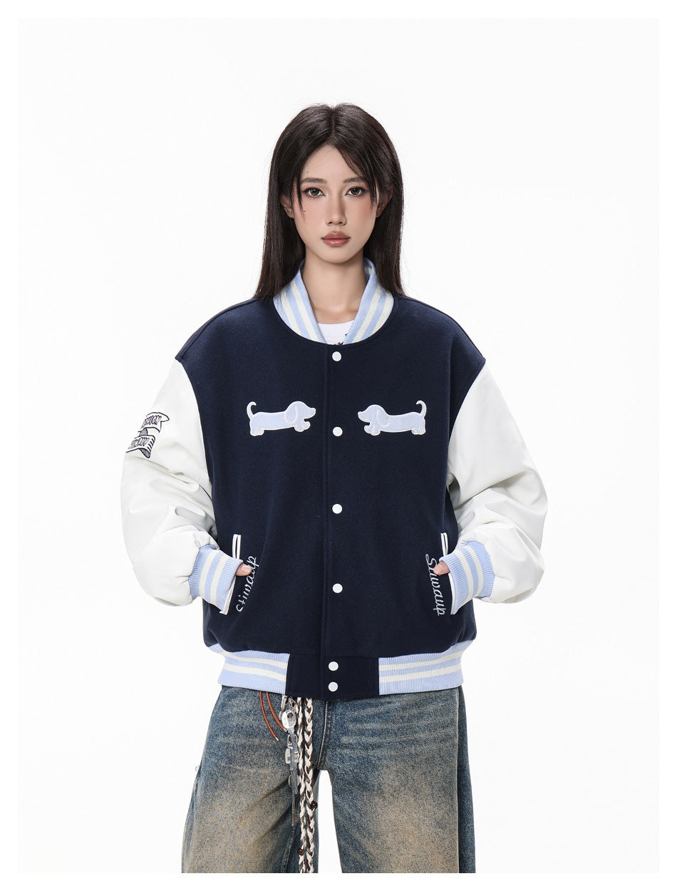 Model wearing a navy varsity jacket with white sleeves, pale blue striped trim and two dog appliqués on the chest.