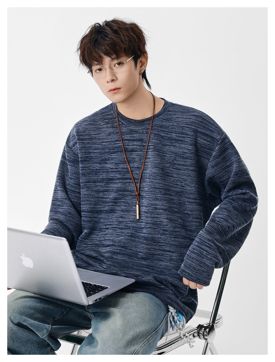 Model in a blue heathered crew-neck pullover seated with a laptop, close-up showing the knit texture