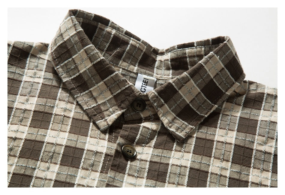 Brown, beige and gray plaid shirt collar and upper placket with two dark buttons and a partially visible neck label.