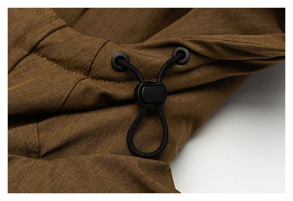 Close-up of a black cord lock and drawcord threaded through eyelets on the brown jacket.