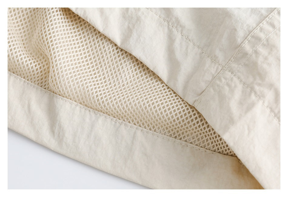Close-up of cream pants opened to reveal a mesh lining and stitched fabric edges.