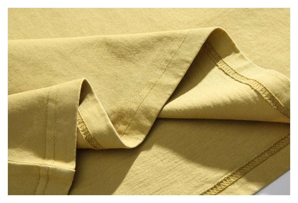 Close-up of the pale yellow T-shirt hem, showing the folded edge and overlocked inner stitching.