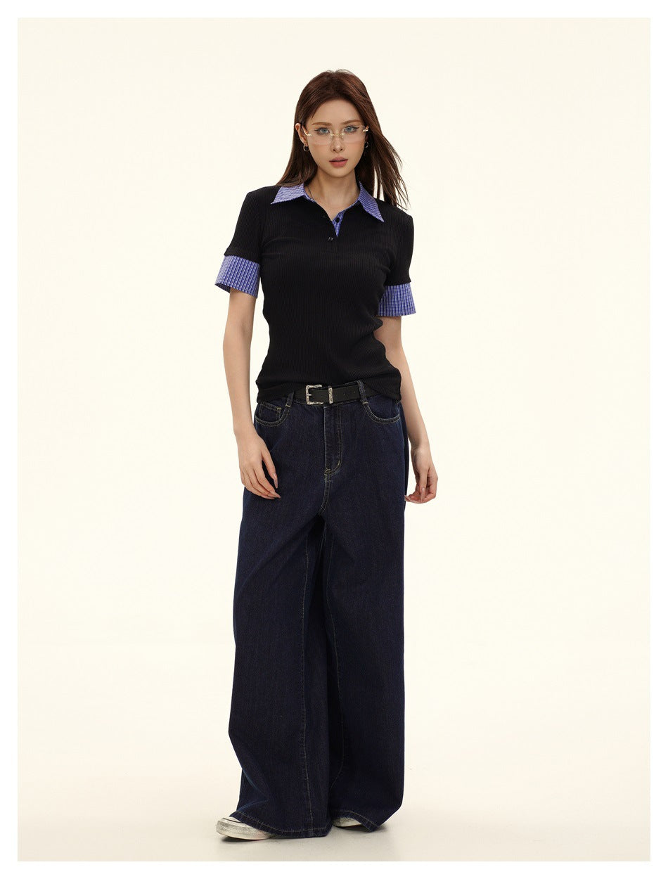 Model in black ribbed polo top with plaid collar and cuffs, standing with arms at sides, dark wide-leg jeans