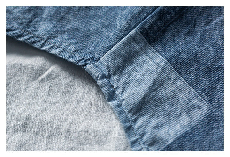 Close-up of a curved stitched seam and folded edge on blue denim, with the lighter reverse side visible.