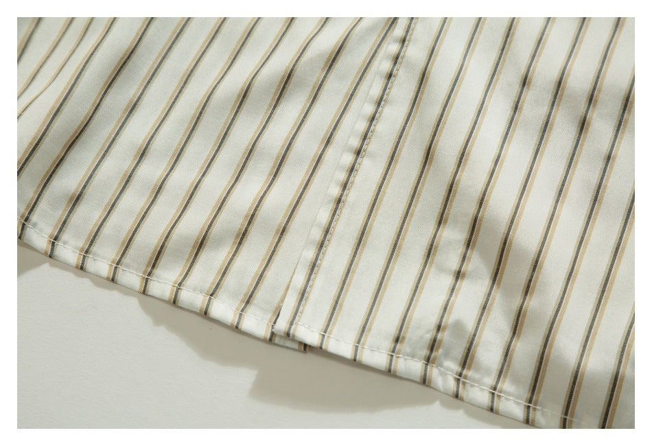 Close-up of an ivory shirt hem with narrow tan and dark gray vertical stripes and visible stitching.