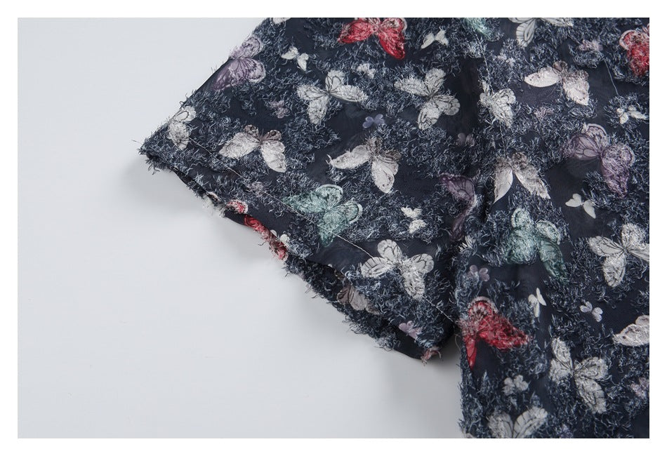 Close-up of the navy butterfly-print shirt's short sleeve and textured edge.