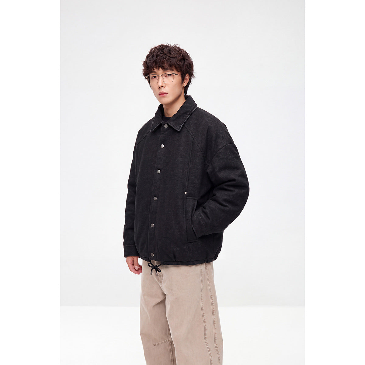 Model wearing a black button-front jacket with a pointed collar and large front pockets.