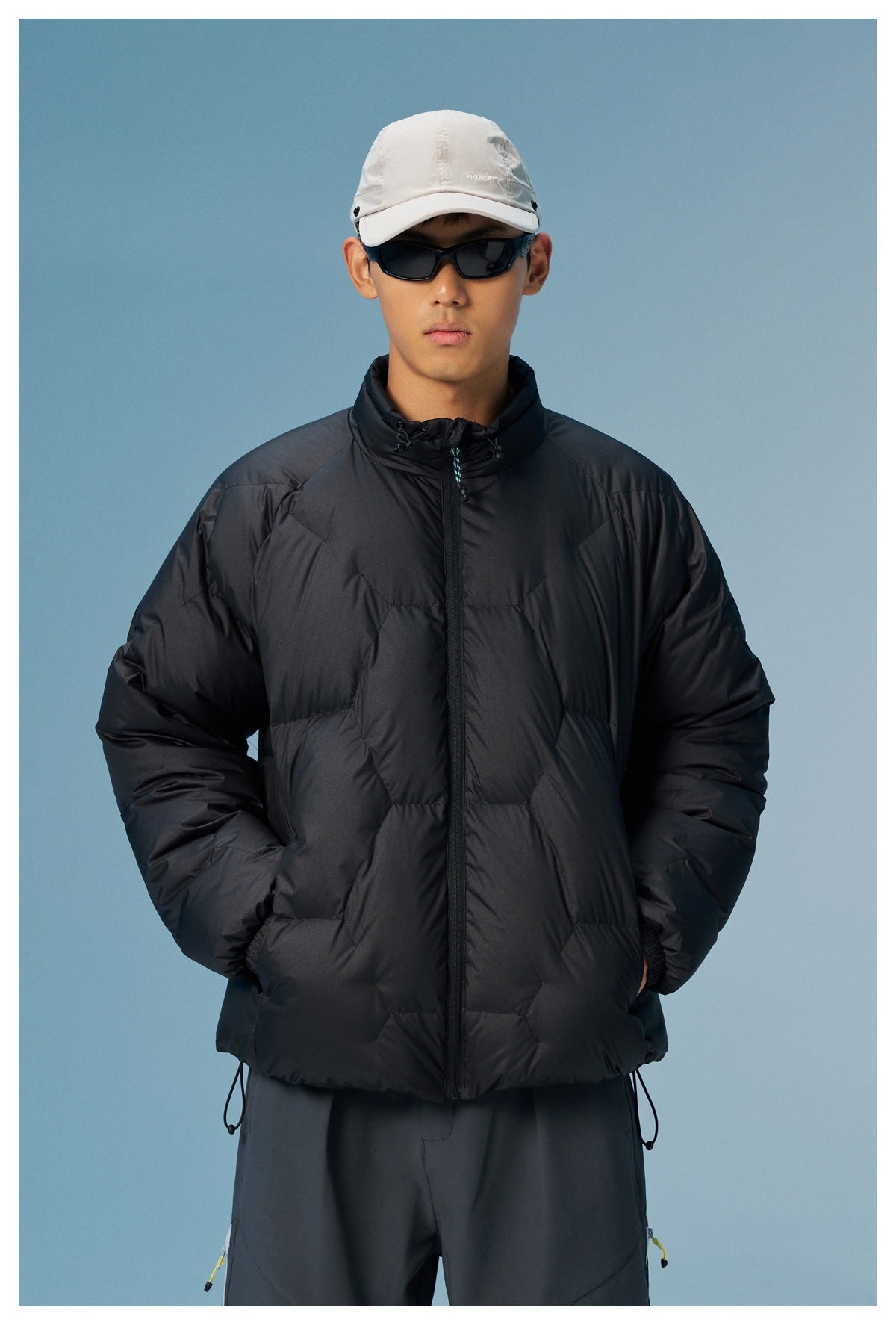 Front view of a man wearing a black quilted puffer jacket with a zip front and high collar.
