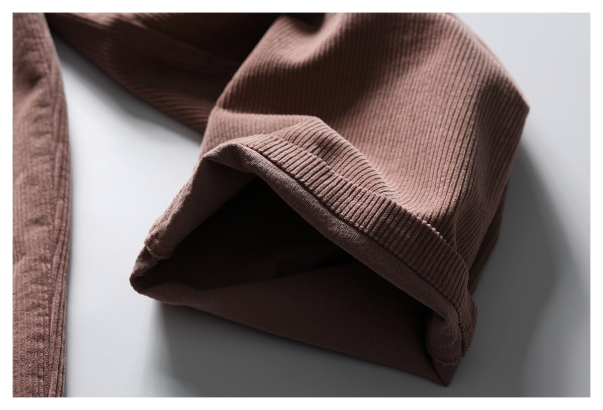 Close-up of the folded hem opening on dusty mauve-brown ribbed trousers.