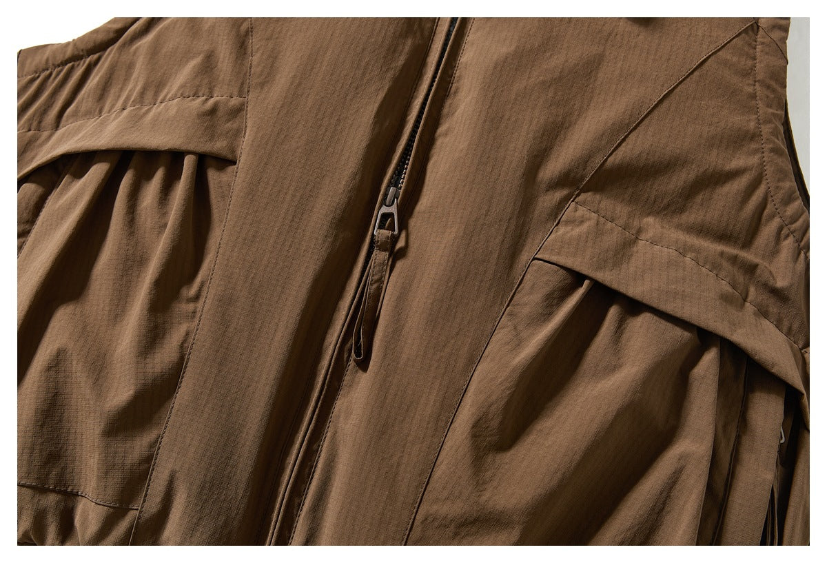 Close-up of the brown vest's front zipper, panel seams, and pleated side pocket.