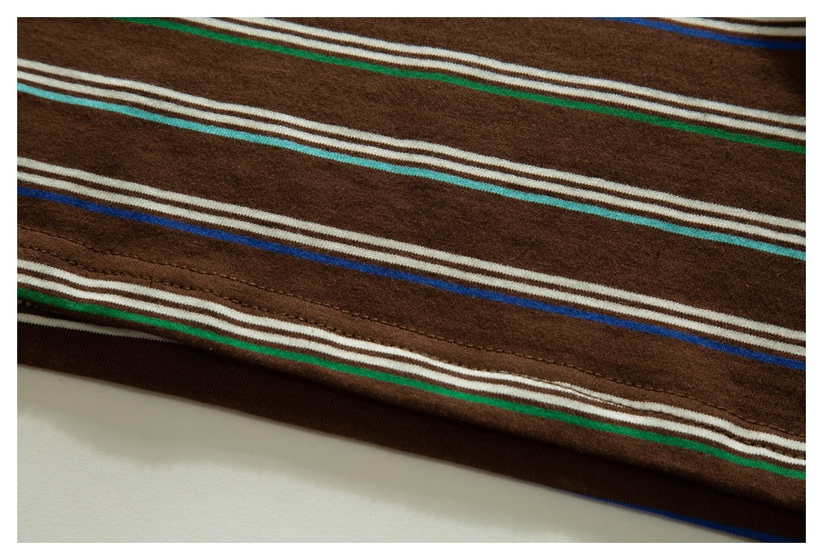 Close-up of brown striped garment fabric showing a stitched hem and cream, turquoise, green and blue lines.