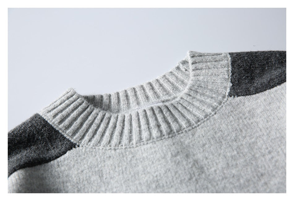 Close-up of a light gray sweater’s ribbed crew neck and charcoal shoulder panels.