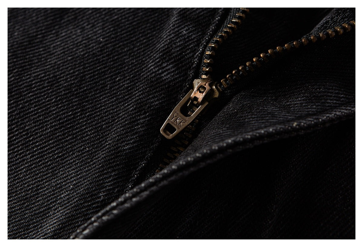 Close-up of a metal zipper and pull on black denim jeans.