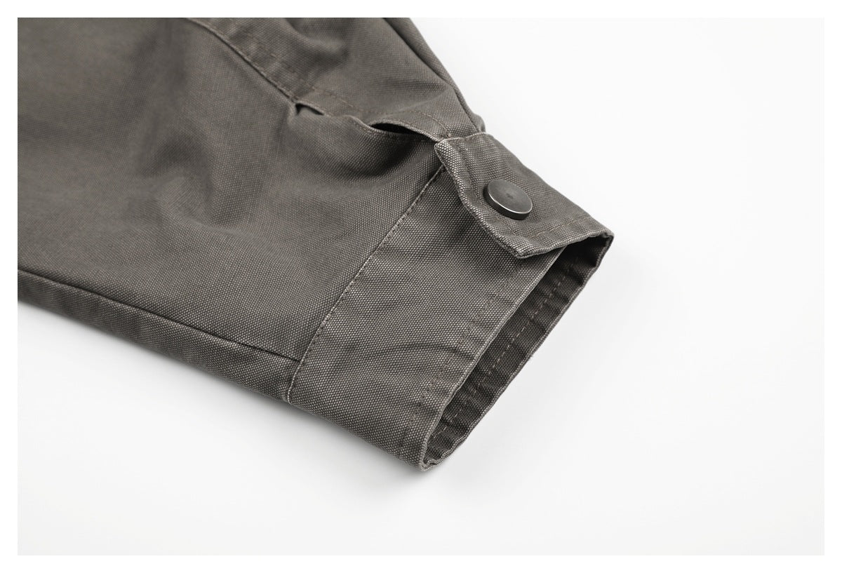 Close-up of a dark gray garment cuff with a buttoned tab and visible stitching.