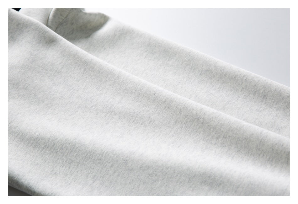 Close-up of the light gray heather garment fabric, with part of a black-trimmed edge visible.