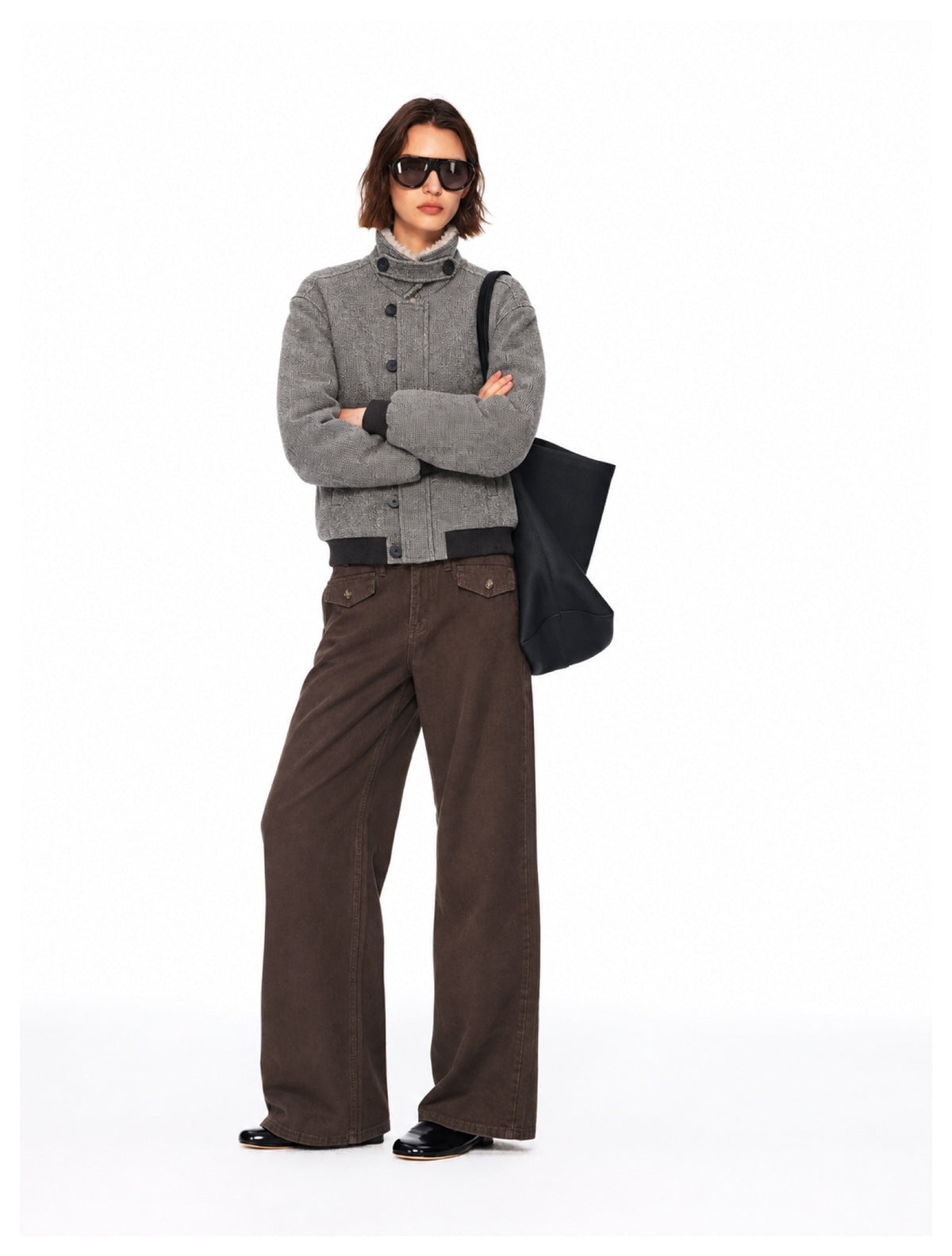 Model wearing a gray high-collar jacket with black ribbed cuffs and hem, and wide-leg brown pants.