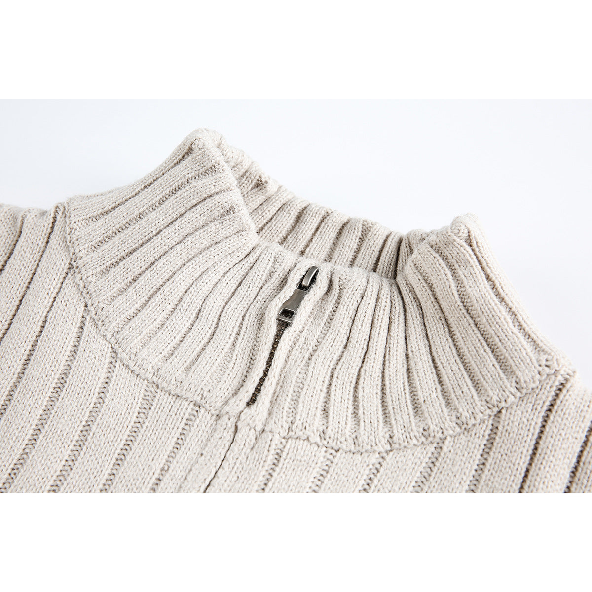 Close-up of an ivory ribbed knit sweater's tall collar and short metal zipper.