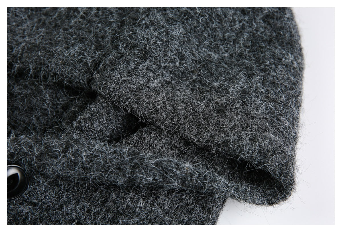 Close-up of a folded edge and black button on charcoal gray fuzzy knit fabric.