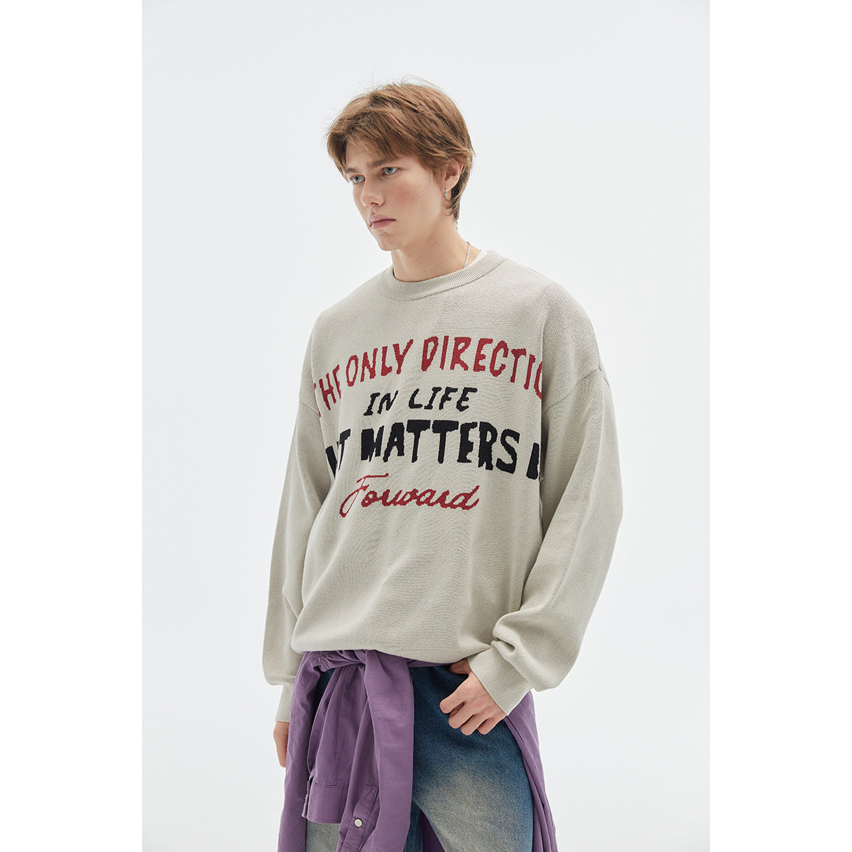 Close view of a model wearing a light gray sweatshirt with red and black slogan lettering.