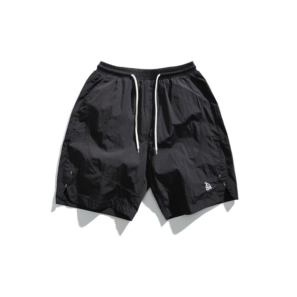 Black knee-length shorts with elastic waist, white drawstring, and small embroidered sailboat, flat lay front view