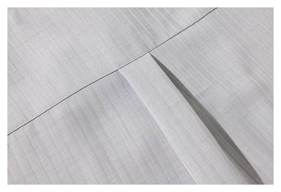 Close-up of a stitched seam and pleat in light gray fabric with fine stripes.